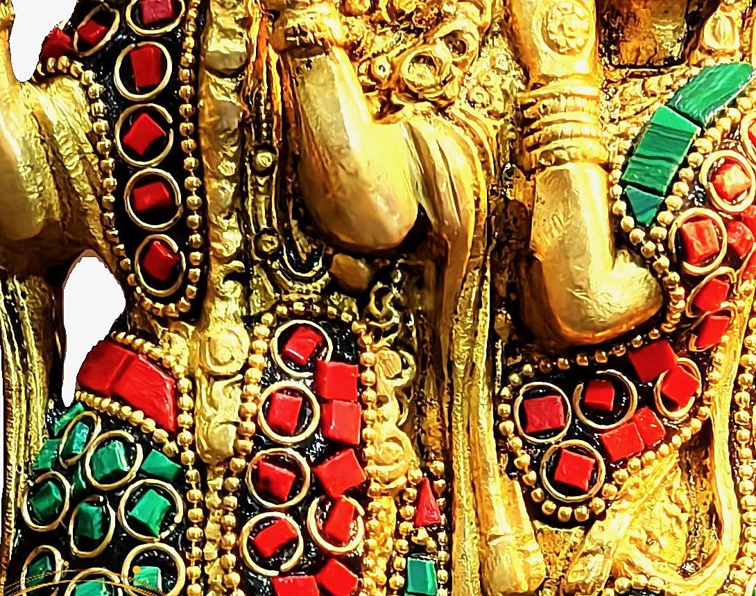Close-up of hand-set coral and malachite stone inlay on a brass Radha Krishna idol showing natural variation between stones
